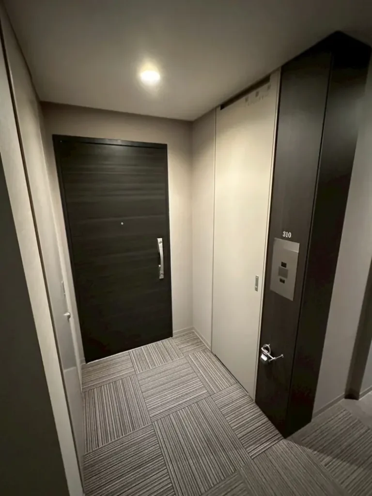 神戸ハーバーランドの高級マンション共用廊下と玄関ドアの写真。落ち着いた色合いの内装。